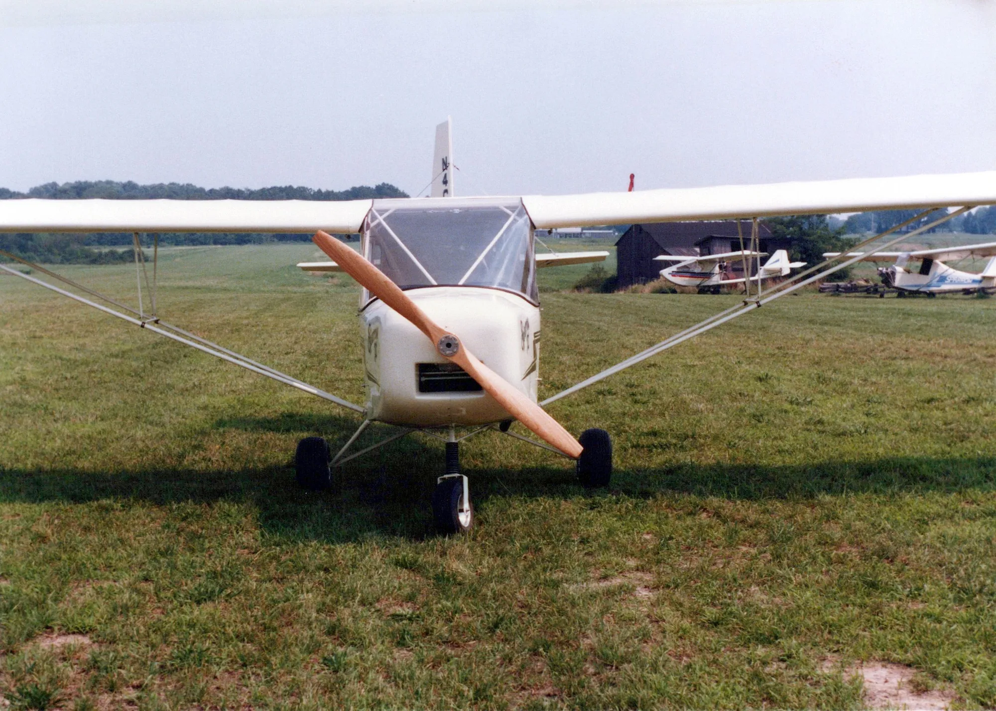 A white Carlson Sparrow II seen head-on on a grass airfield, propeller stopped