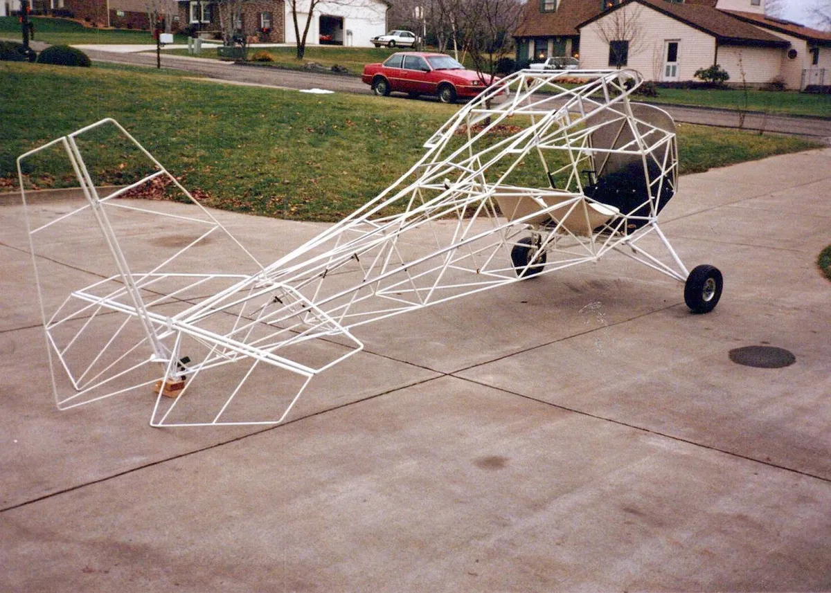 A bare welded steel-tube fuselage frame of a Carlson Sparrow on a driveway