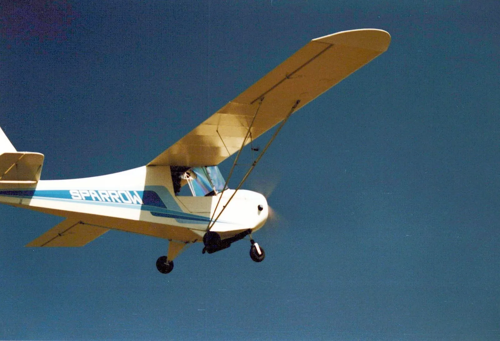 A white and blue Carlson Sparrow banking against a clear blue sky